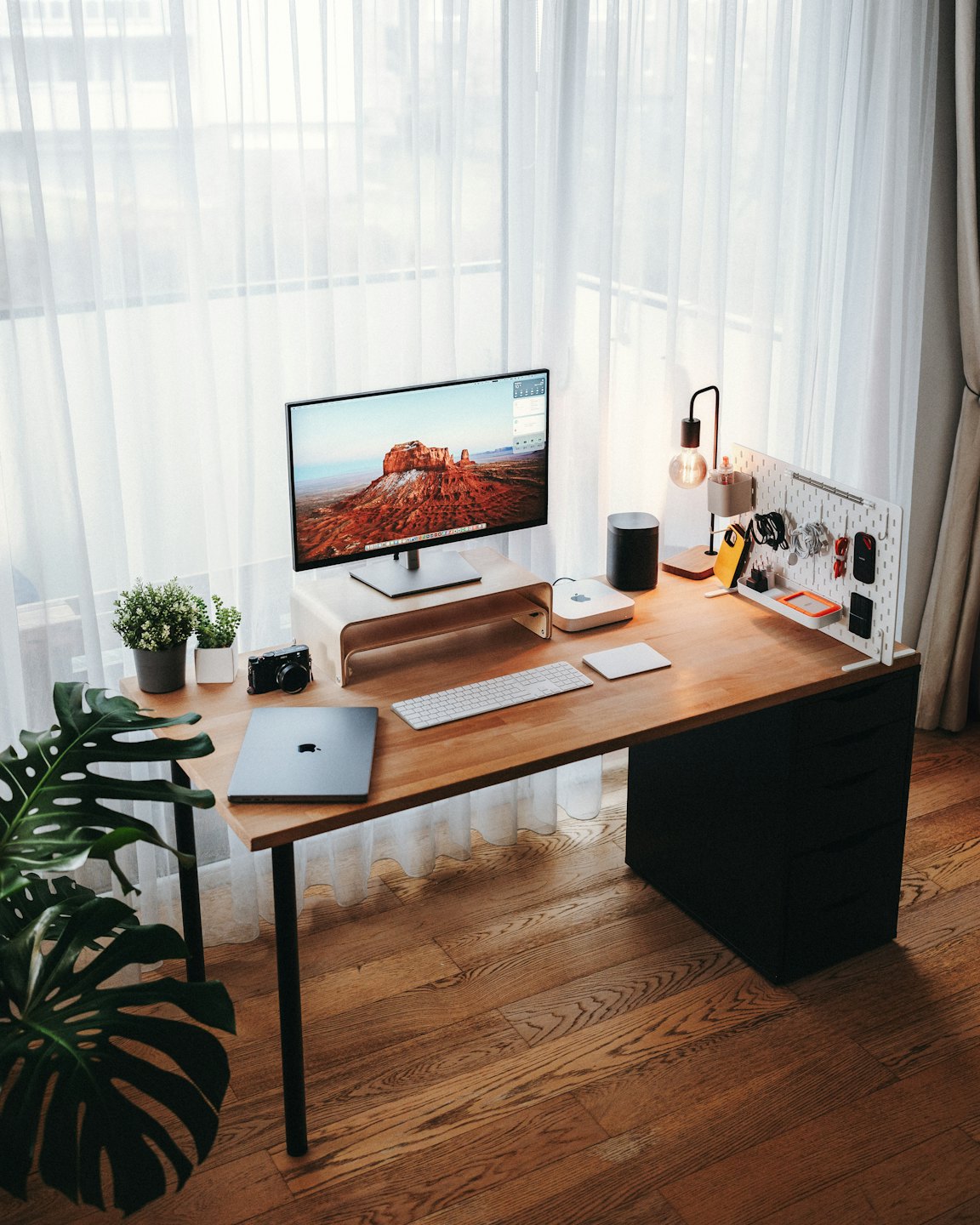 Modern home office desk with computer accessories by a window.